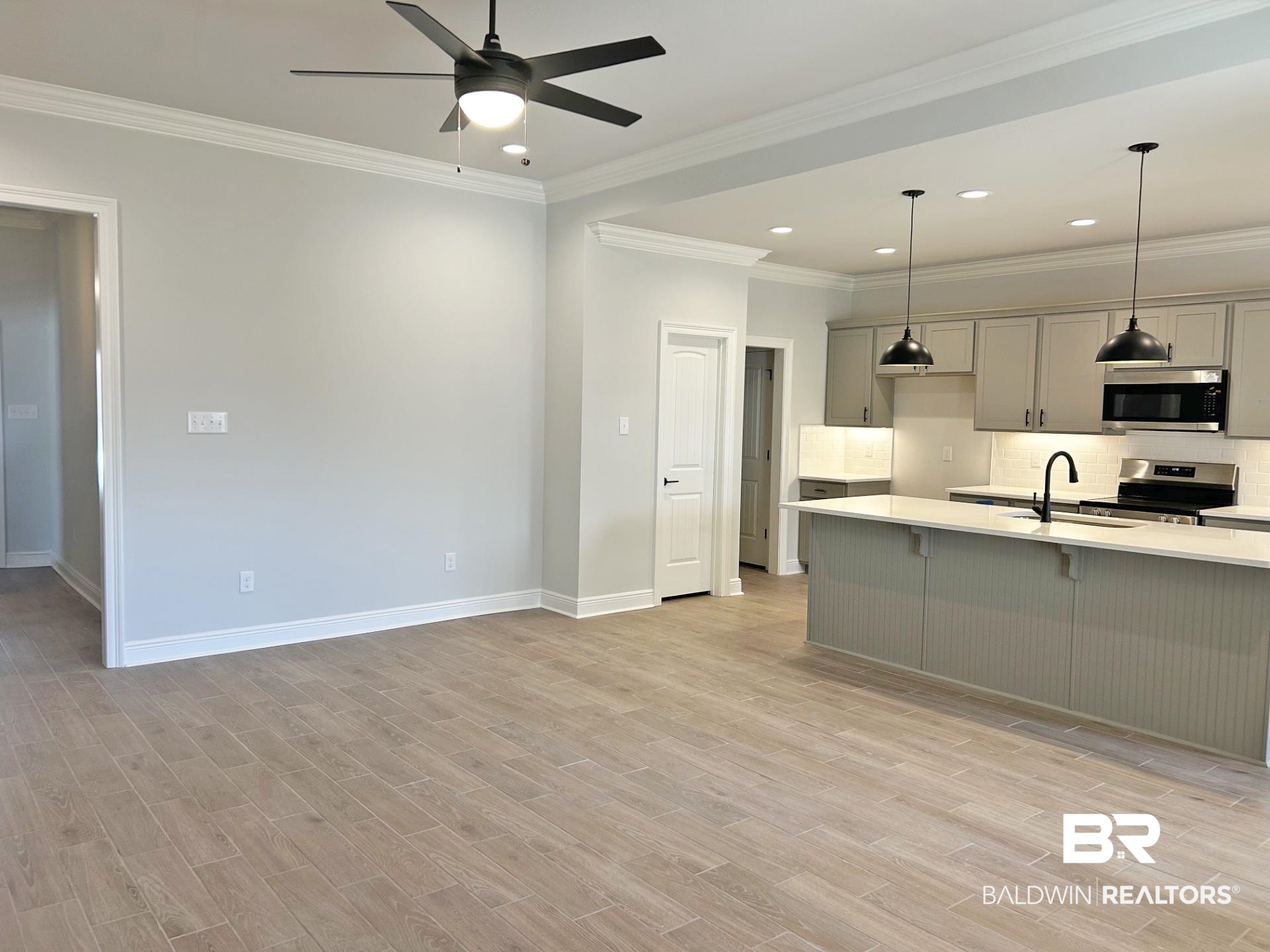 825 Sumter Loop Foley, AL 36535 - Photo 6 of 21 Kitchen with gray cabinetry, appliances with stainless steel finishes, a kitchen bar, decorative light fixtures, and crown molding