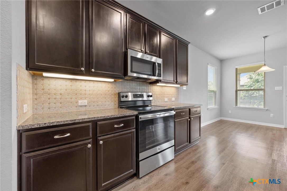 5338 Fenton Lane Belton, TX 76513 - Photo 10 of 33 a kitchen with stainless steel appliances granite countertop wooden cabinets and a stove top oven