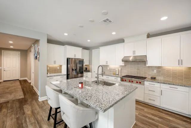 a kitchen with stainless steel appliances granite countertop a sink refrigerator and cabinets