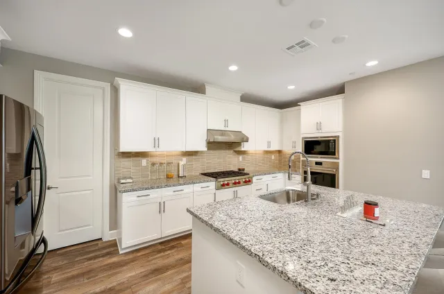 a kitchen with stainless steel appliances granite countertop a sink refrigerator and cabinets