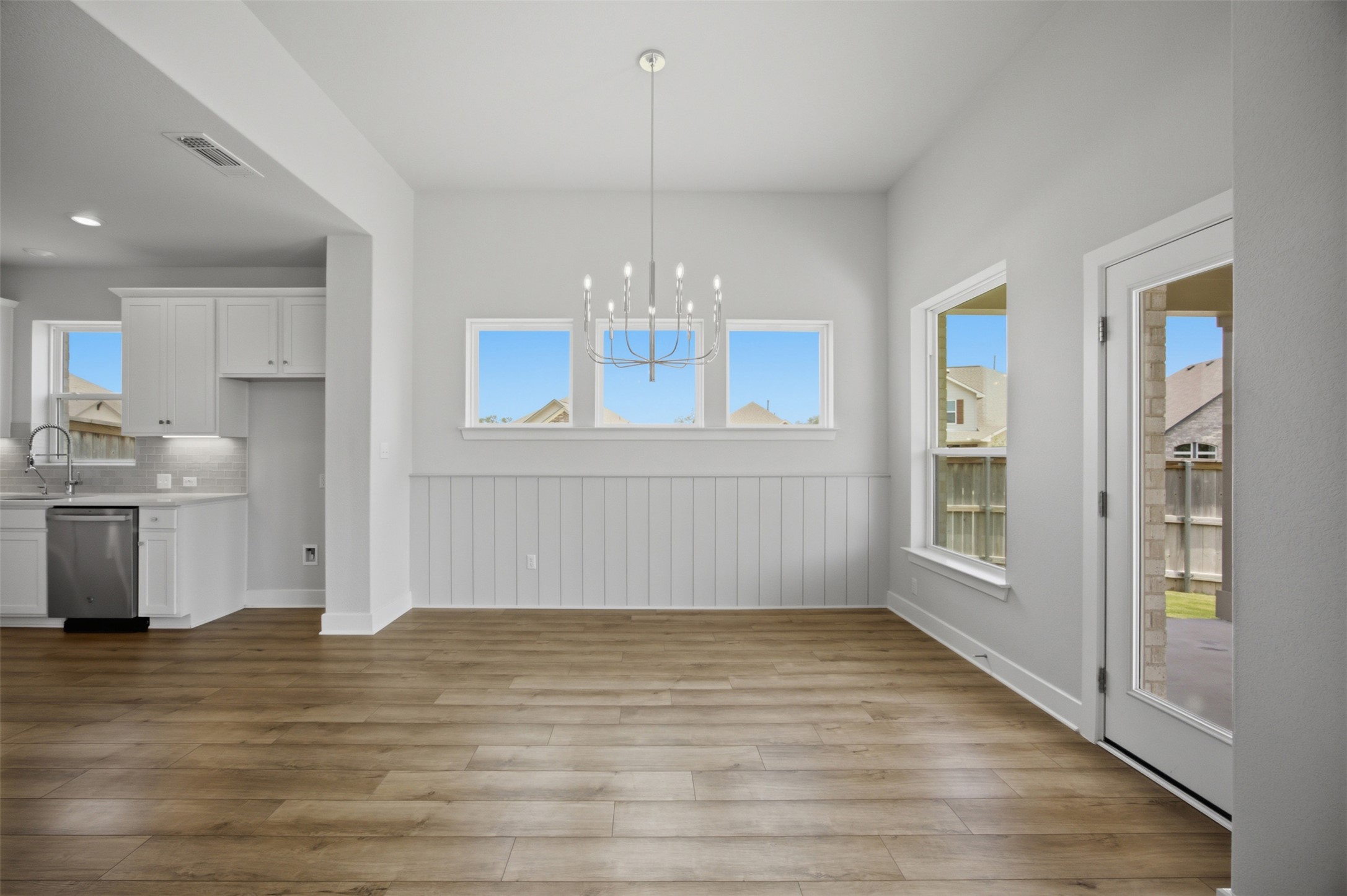 2101 Little Snake Way Georgetown, TX 78633 - Photo 15 of 37 A sleek chandelier illuminates this spacious dining area with wood flooring and wainscoting details.
