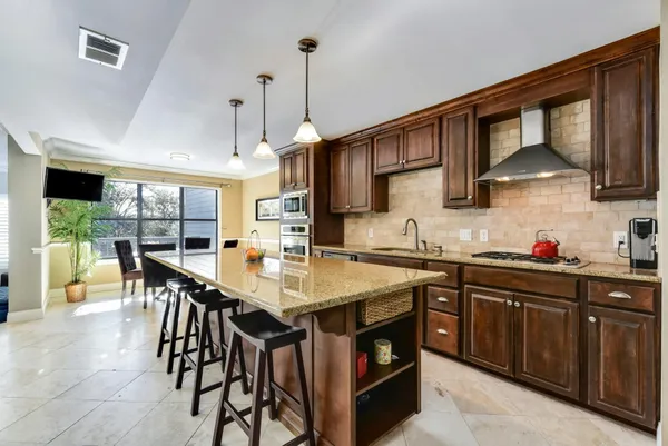 a kitchen with stainless steel appliances granite countertop a sink a stove and a wooden floors