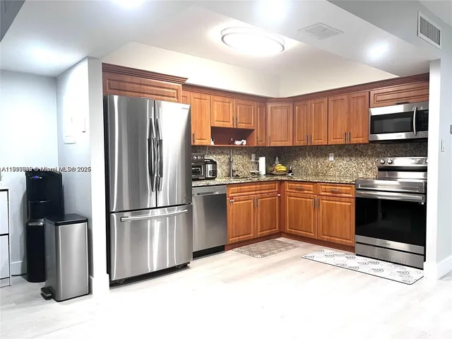 a kitchen with granite countertop a refrigerator stove and microwave