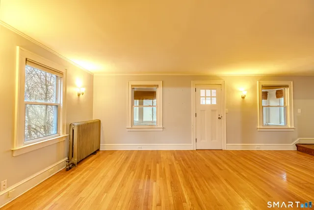 a view of an empty room with a window and wooden floor