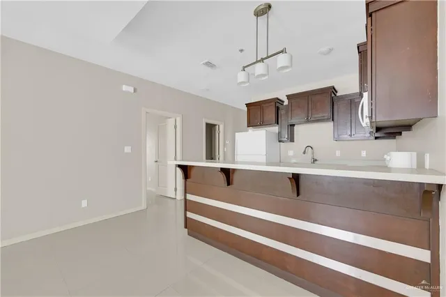 a spacious kitchen with stainless steel appliances a sink dishwasher a refrigerator and white cabinets with wooden floor