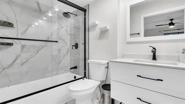 a bathroom with a sink a mirror a toilet and shower