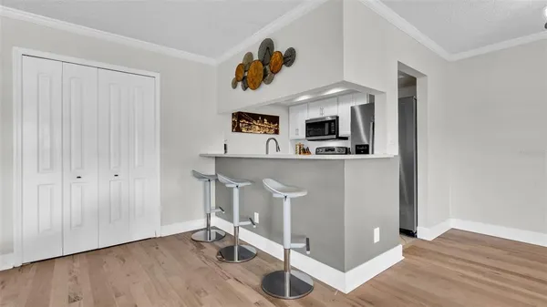 a living room with kitchen island stainless steel appliances wooden floor and a window