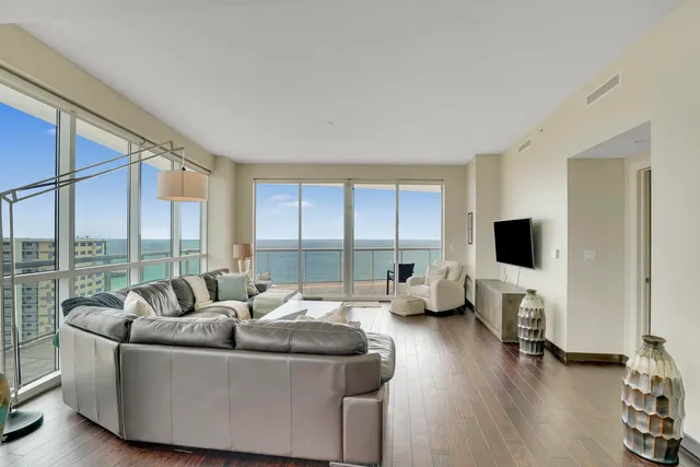 a living room with furniture floor to ceiling window and a flat screen tv