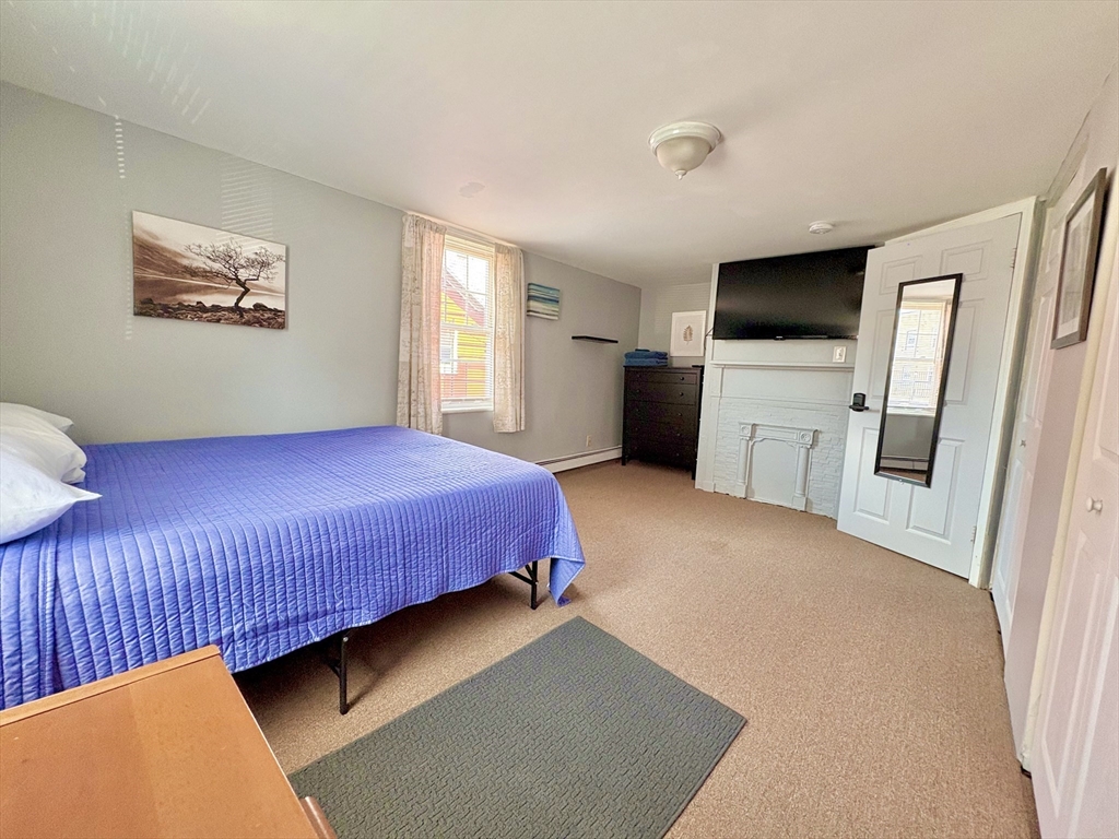 285 Roxbury Street Boston, MA 02119 - Photo 10 of 15 a bedroom with a bed a wall painting and a window