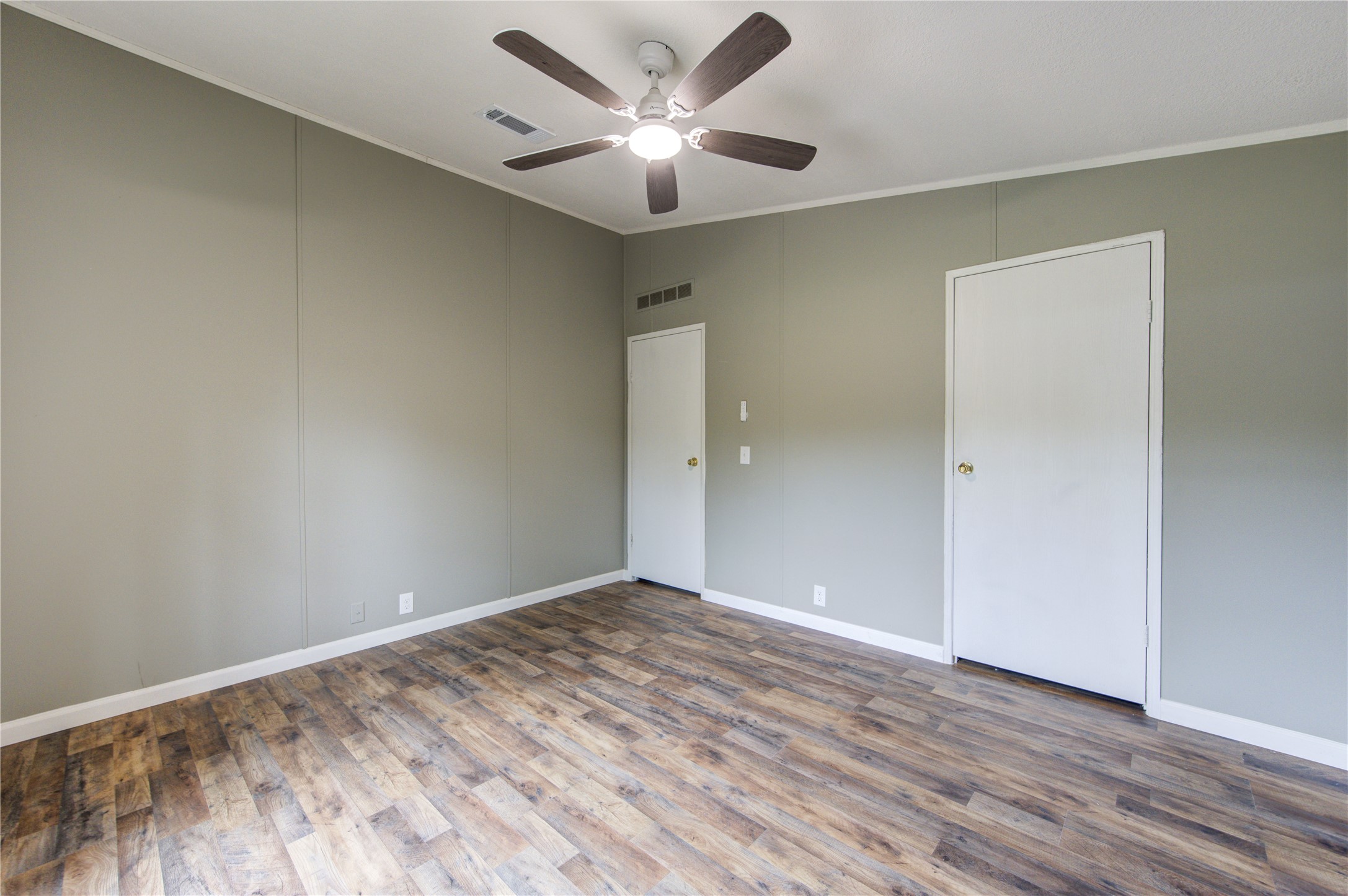 30226 Davis Street Magnolia, TX 77355 - Photo 38 of 50 This room features neutral-colored walls, wood-style flooring, and a ceiling fan, creating a modern and inviting space. It includes two doors for additional access or storage.