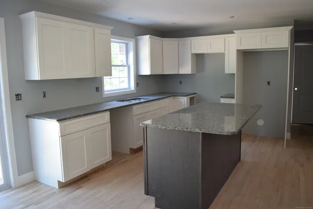 a kitchen with granite countertop white cabinets and a wooden floor