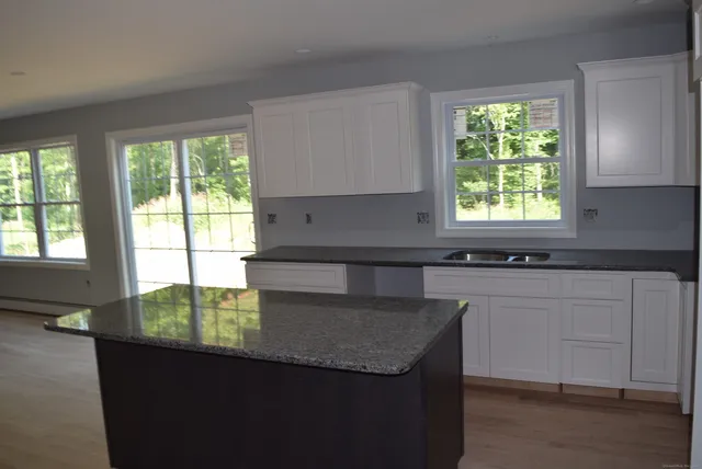 a kitchen with granite countertop a sink window and cabinets