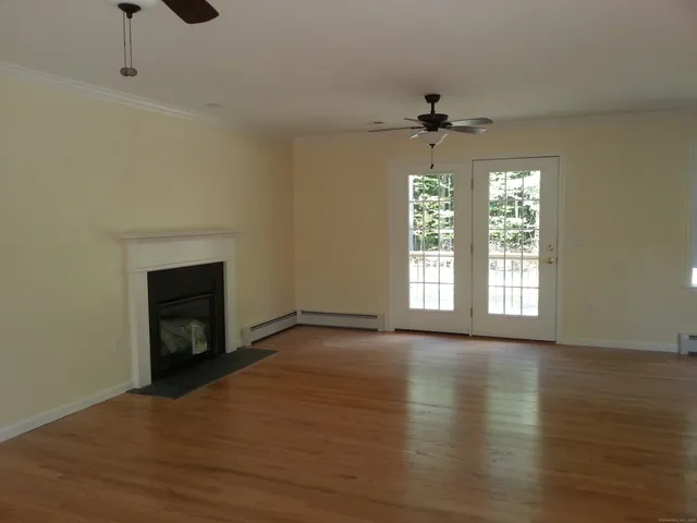 an empty room with wooden floor fireplace and windows