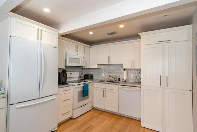 a kitchen with white cabinets and white appliances