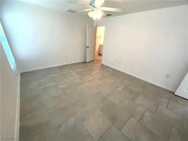 an empty room with a chandelier fan and windows