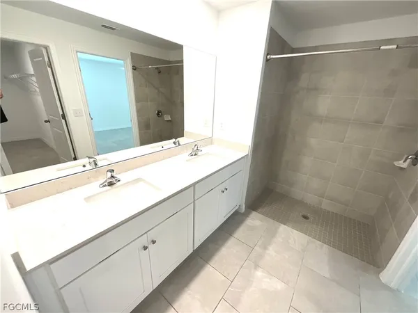 a spacious bathroom with a double vanity sink mirror and shower