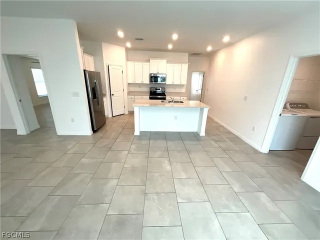 a view of kitchen with stainless steel appliances granite countertop a stove a sink a refrigerator a microwave and cabinets
