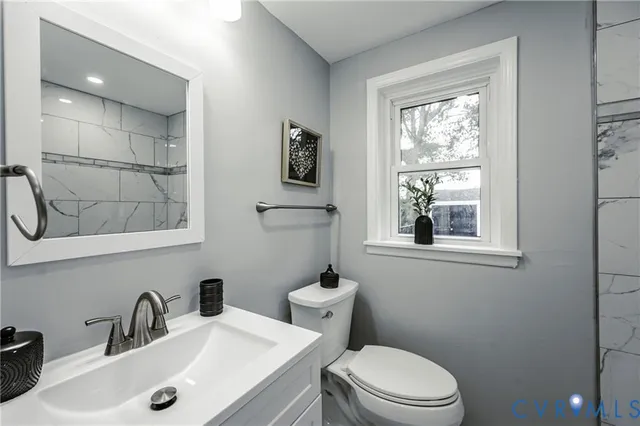 a bathroom with a sink a toilet a mirror and a window