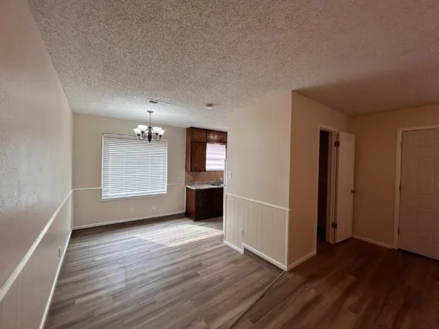 an empty room with wooden floor cabinet and windows