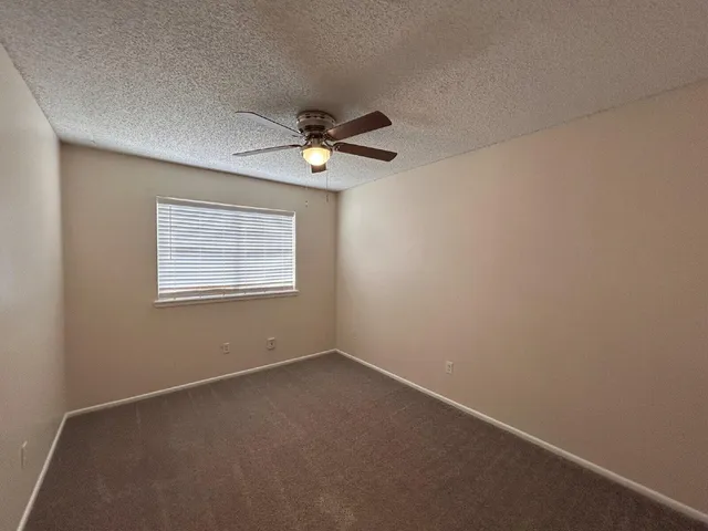 an empty room with a window and a fan