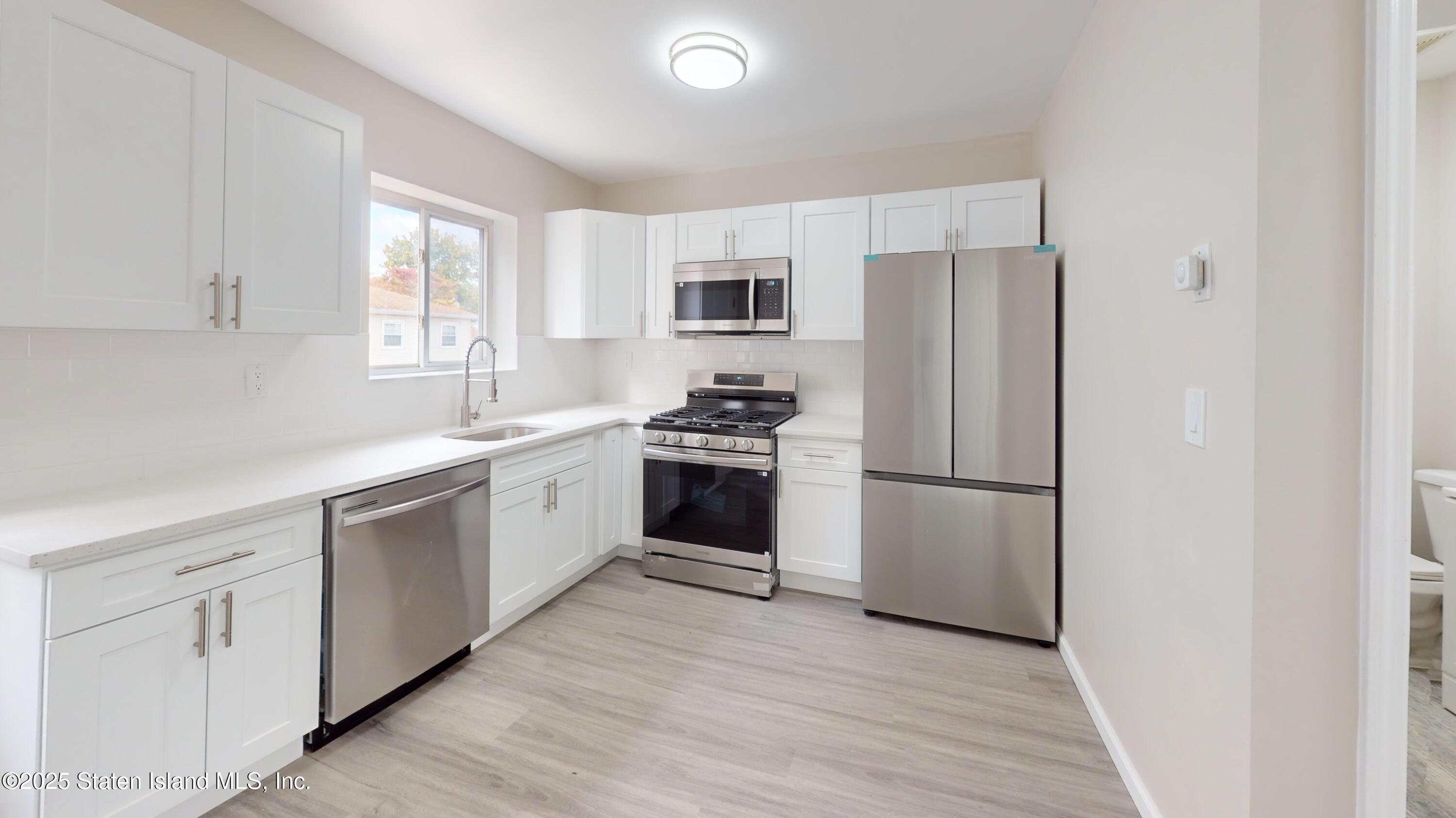 109 Lyceum Court Staten Island, NY 10310 - Photo 14 of 32 a kitchen with white cabinets and white appliances