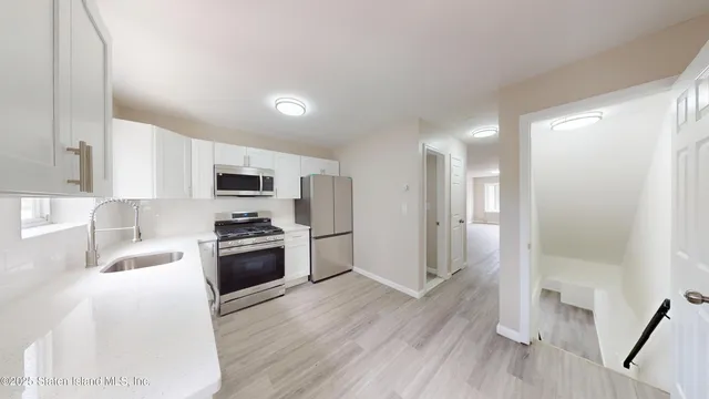 a kitchen with stainless steel appliances granite countertop a refrigerator a sink dishwasher a stove and white countertops with wooden floor