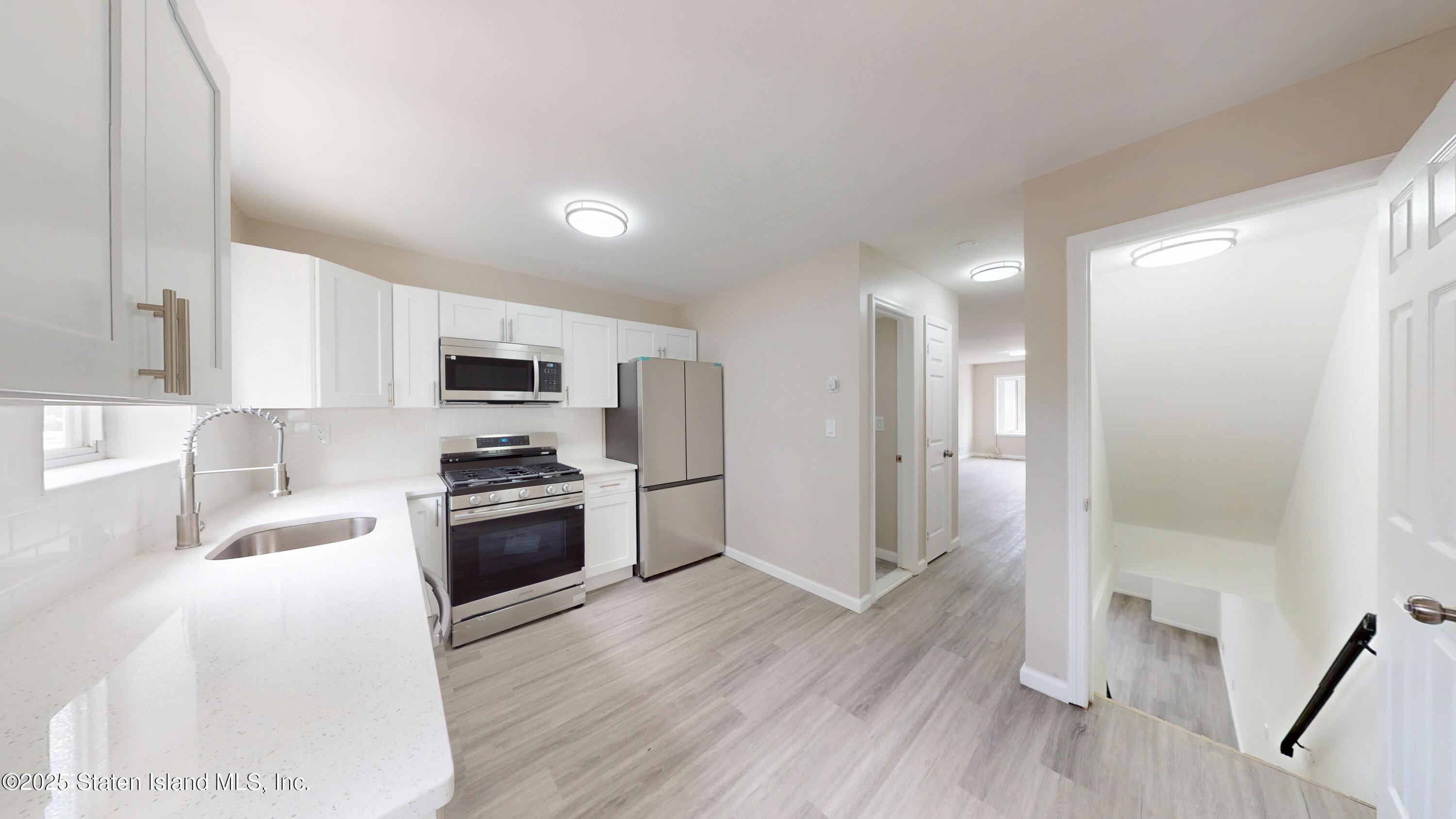 109 Lyceum Court Staten Island, NY 10310 - Photo 15 of 32 a kitchen with stainless steel appliances granite countertop a refrigerator a sink dishwasher a stove and white countertops with wooden floor