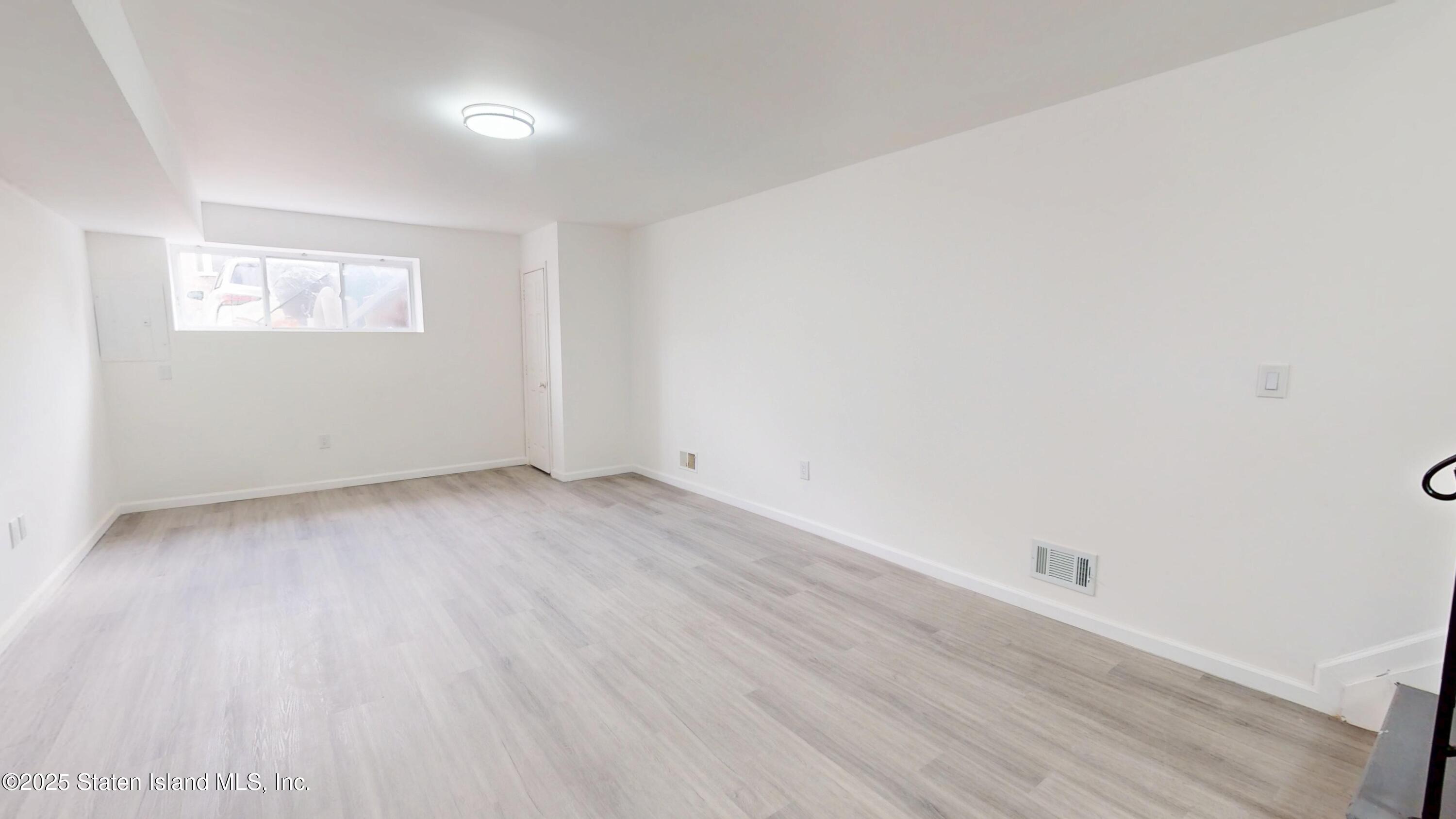 109 Lyceum Court Staten Island, NY 10310 - Photo 8 of 32 an empty room with wooden floor and windows
