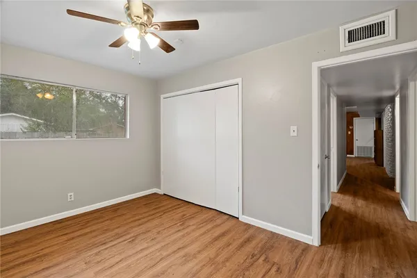 a view of empty room with wooden floor and fan