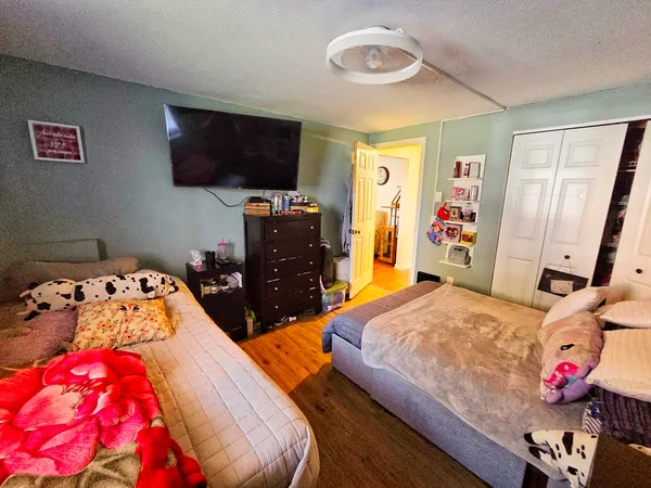 a bedroom with a bed and flat tv screen on the dresser