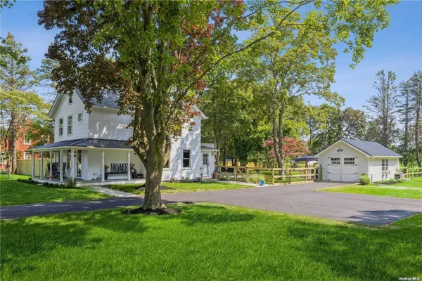 a front view of a house with garden and trees