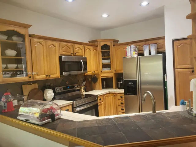 a kitchen with stainless steel appliances granite countertop a sink refrigerator and microwave