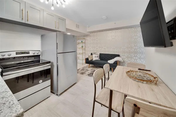 a kitchen with stainless steel appliances a stove a refrigerator a sink a dining table and chairs with wooden floor