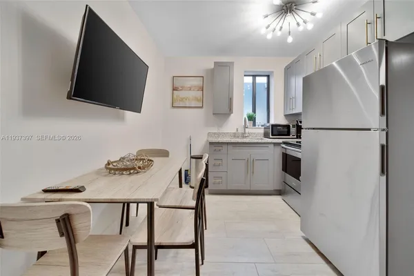 a kitchen with stainless steel appliances a white table chairs and a refrigerator