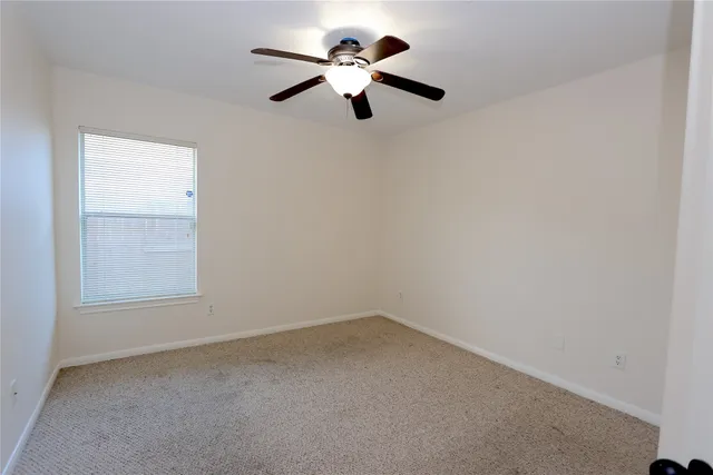 an empty room with a window and a ceiling fan