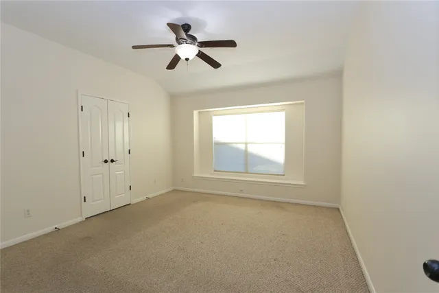 an empty room with a window and a fan