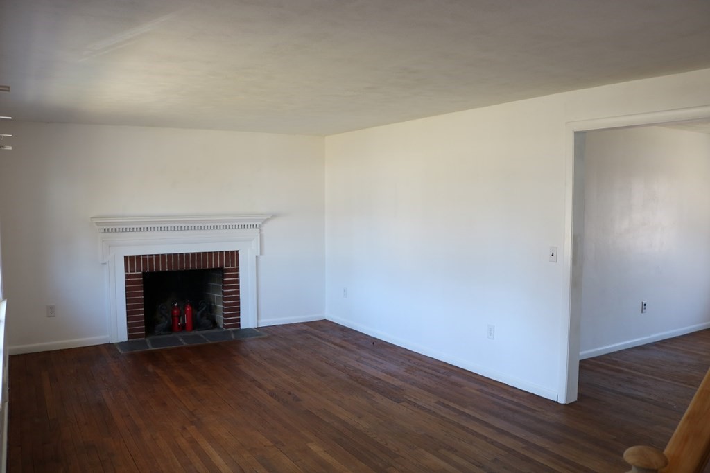 172 East Allen Ridge Road Springfield, MA 01118 - Photo 6 of 20 a view of an empty room with wooden floor and a fireplace