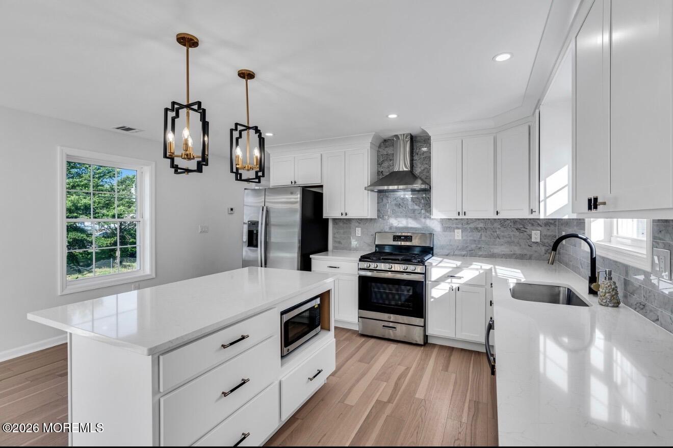 214 Raritan Street Union Beach, NJ 07735 - Photo 10 of 10 a kitchen with stainless steel appliances granite countertop a sink dishwasher a stove a microwave oven and a dining table with wooden floor