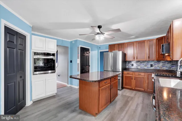 a kitchen with stainless steel appliances granite countertop a refrigerator a sink dishwasher a stove and a large window with wooden floor