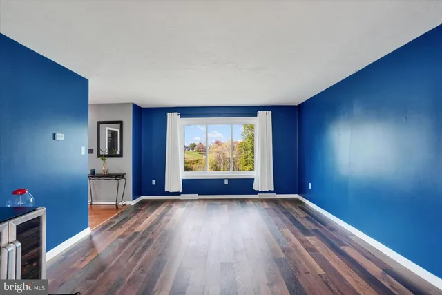 a view of an empty room with a window and wooden floor