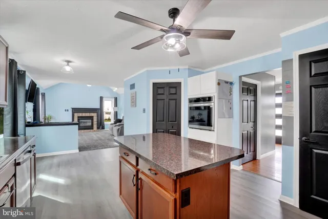 a kitchen with stainless steel appliances granite countertop a refrigerator a stove a sink a dining table and chairs with wooden floor