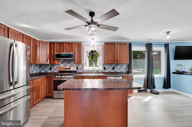 a kitchen with stainless steel appliances granite countertop a refrigerator and a stove top oven