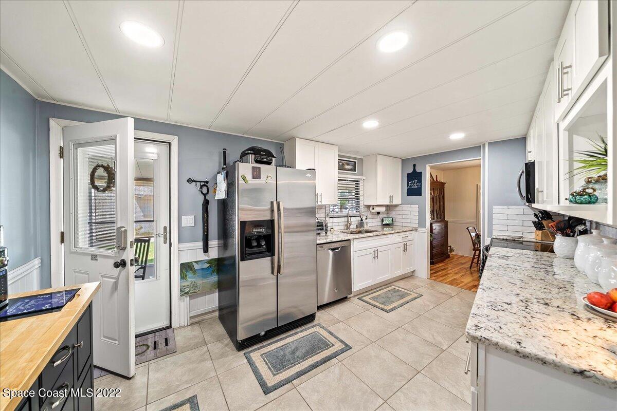 3256 Nancy Avenue Mims, FL 32754 - Photo 9 of 36 a large white kitchen with granite countertop a stove a sink dishwasher a refrigerator and cabinets with wooden floor