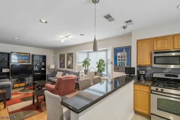 a kitchen with stainless steel appliances granite countertop a stove top oven a sink a dining table and chairs