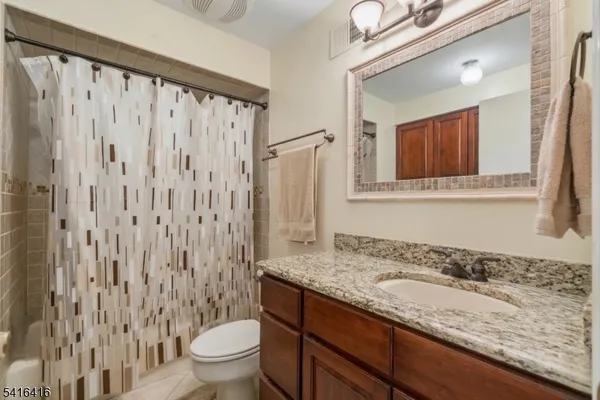a bathroom with a granite countertop sink a toilet and a mirror
