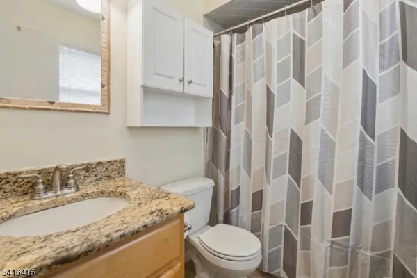 a bathroom with a granite countertop sink a toilet and shower