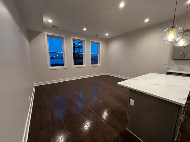 a view of kitchen with stainless steel appliances wooden floor dining table and chairs