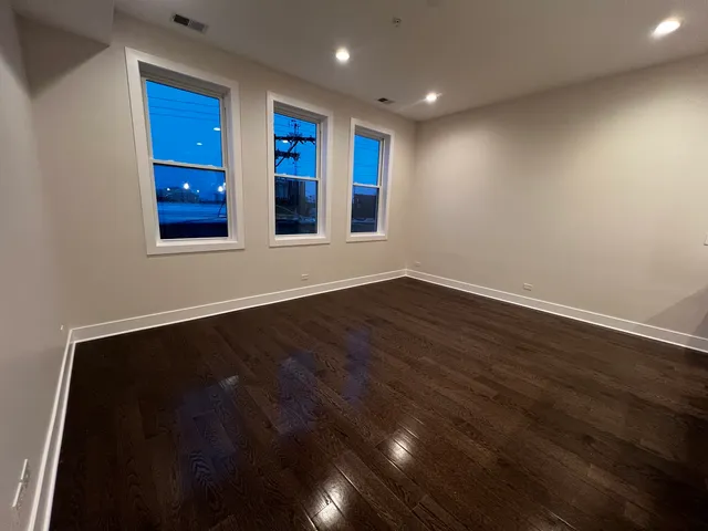a view of an empty room with wooden floor and windows