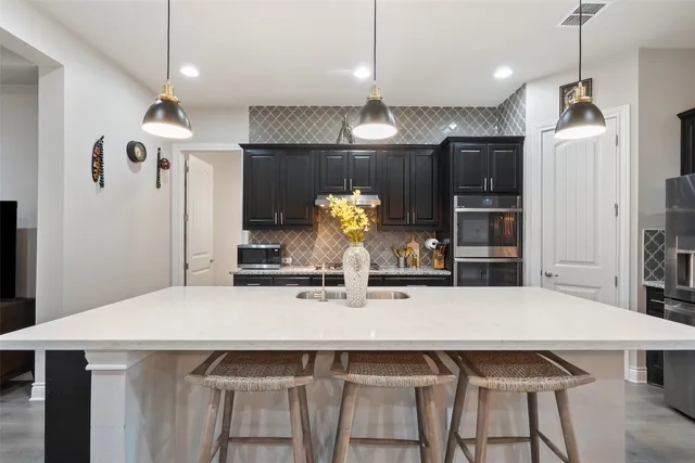 a kitchen with stainless steel appliances a dining table chairs and refrigerator