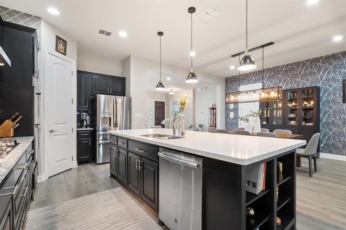 225 Escarpment Way Cedar Park, TX 78613 - Photo 10 of 40 a large kitchen with stainless steel appliances kitchen island granite countertop a table chairs in it and wooden floors